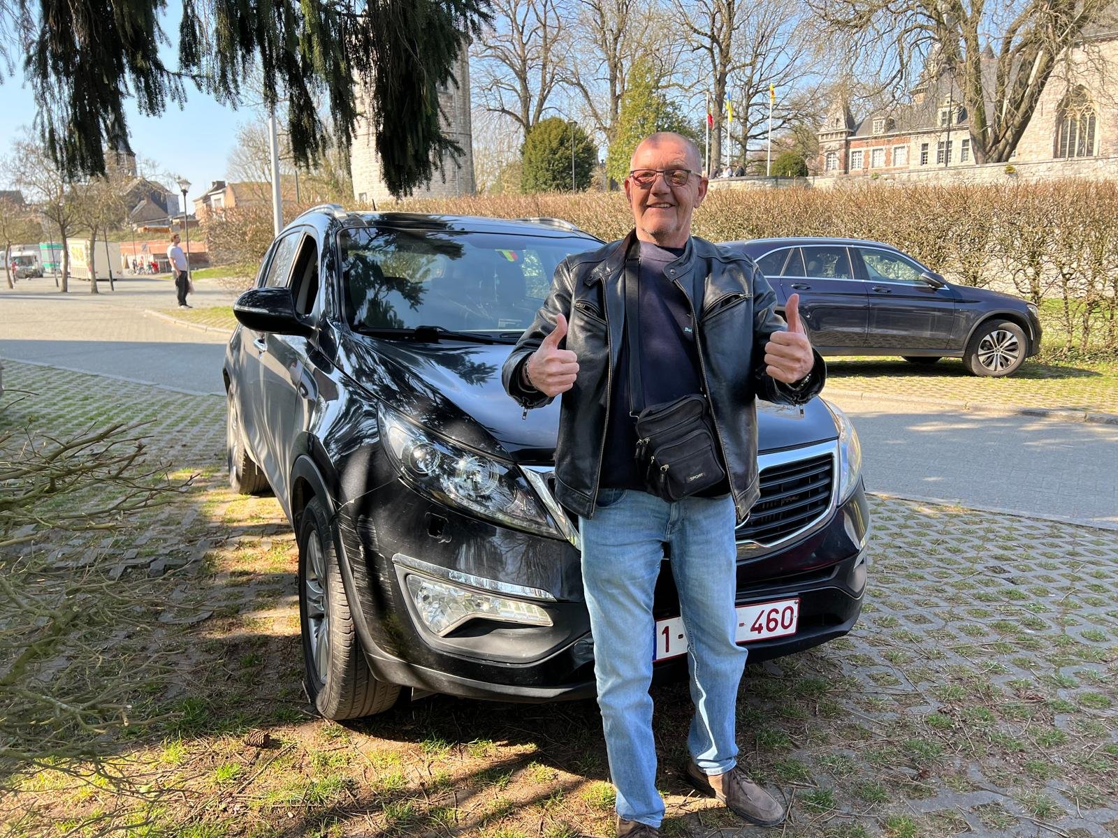 Zwarte Kia Sportage uit 2013 met een man voor de wagen