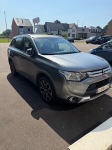 Grijze Mitsubishi Outlander, buiten gefotografeerd van schuin vooraan.