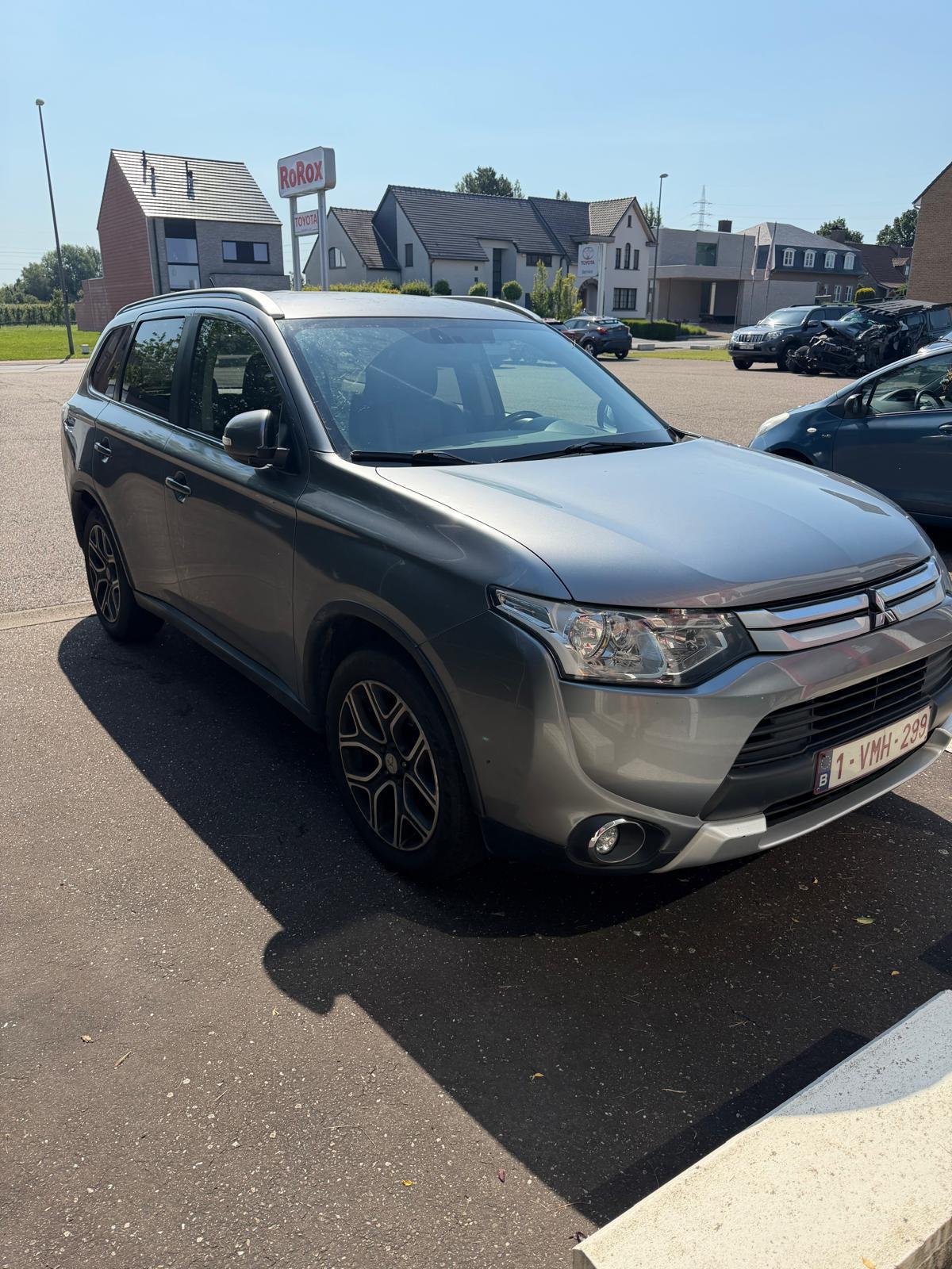 Grijze Mitsubishi Outlander, buiten gefotografeerd van schuin vooraan.